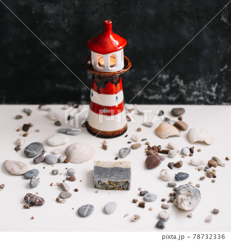 A small decorative lighthouse with sea shells and pebbles. Summer, holidays and vacation concept 78732336