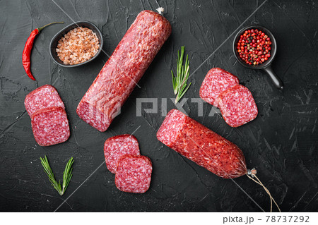 Traditional smoked salami sausage with spices, on black dark stone table background, top view flat lay 78737292