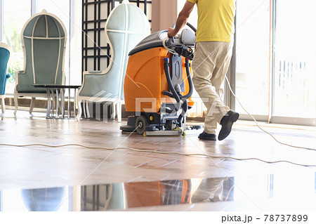 Janitor is cleaning hall with washing vacuum cleaner closeup 78737899