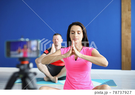 Man and woman sitting in lotus position on gymnastic mats in front of camera 78737927