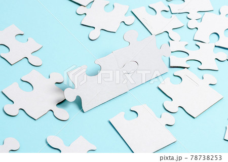 Close-Up White Jigsaw Pattern Puzzle Pieces To Be Connected With Missing Last Piece Positioned On A Flat Lay Background With Different Texture And Paper Supplies Accesories Close-Up White Jigsaw Pattern Puzzle Pieces To Be Connected With Missing Last Piece Positioned On A Flat Lay Background With Different Texture And Paper Supplies Accesories 78738253