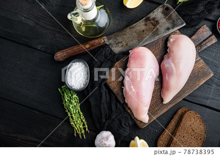 Crumbed uncooked chicken breast ingredient with butcher knife on black wooden table, flat lay with space for text Crumbed uncooked chicken breast ingredient with butcher knife on black wooden table, flat lay with space for text 78738395