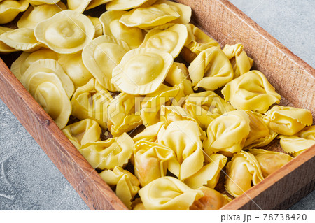 Italian raw handmade Tortellini and Ravioli, in wooden box, on gray background Italian raw handmade Tortellini and Ravioli, in wooden box, on gray background 78738420