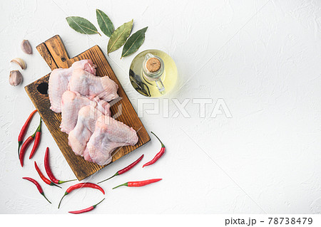 Uncooked chicken wings with spices, on wooden cutting board, on white background, top view flat lay, with copy space for text 78738479