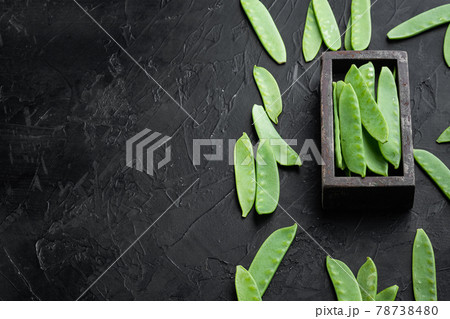 Organic Green Sugar Snap Peas Ready to Eat, in wooden box, on black stone background , with copyspace and space for text 78738480