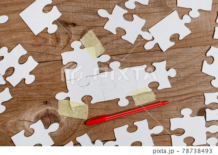 Close-Up White Jigsaw Pattern Puzzle Pieces To Be Connected With Missing Last Piece Positioned On A Flat Lay Background With Different Texture And Paper Supplies Accesories 78738493