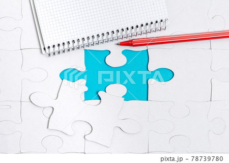 Close-Up White Jigsaw Pattern Puzzle Pieces To Be Connected With Missing Last Piece Positioned On A Flat Lay Background With Different Texture And Paper Supplies Accesories 78739780