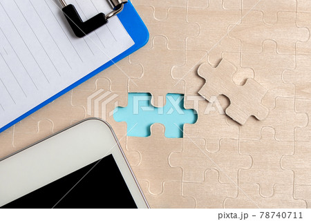 Close-Up White Jigsaw Pattern Puzzle Pieces To Be Connected With Missing Last Piece Positioned On A Flat Lay Background With Different Texture And Paper Supplies Accesories 78740711