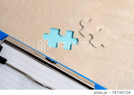 Close-Up White Jigsaw Pattern Puzzle Pieces To Be Connected With Missing Last Piece Positioned On A Flat Lay Background With Different Texture And Paper Supplies Accesories Close-Up White Jigsaw Pattern Puzzle Pieces To Be Connected With Missing Last Piece Positioned On A Flat Lay Background With Different Texture And Paper Supplies Accesories 78740726