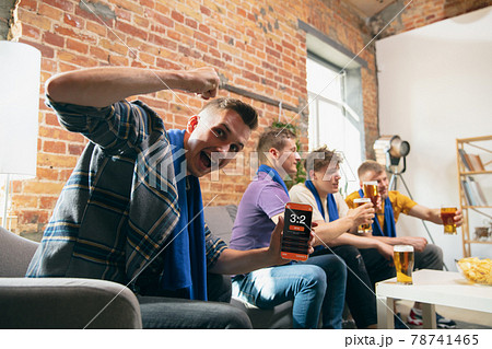 Side view. Young men watching TV, sport match together. Concept of friendship, leisure activity, emotions Side view. Young men watching TV, sport match together. Concept of friendship, leisure activity, emotions 78741465