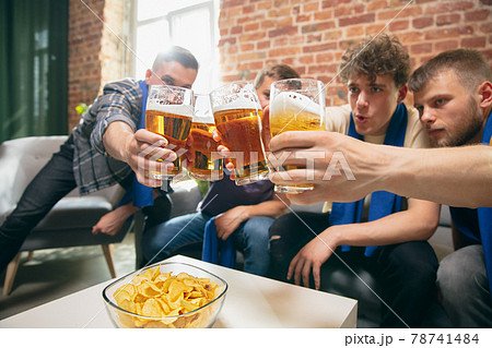 High angle view of young people watching TV, sport match together. Concept of friendship, leisure activity, emotions High angle view of young people watching TV, sport match together. Concept of friendship, leisure activity, emotions 78741484