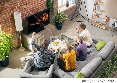 High angle view of young people watching TV, sport match together. Concept of friendship, leisure activity, emotions High angle view of young people watching TV, sport match together. Concept of friendship, leisure activity, emotions 78741492