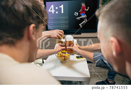 High angle view of young people watching TV, sport match together. Concept of friendship, leisure activity, emotions High angle view of young people watching TV, sport match together. Concept of friendship, leisure activity, emotions 78741555