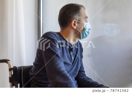 Young man with medical mask looking out the window 78741562