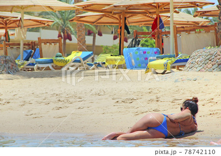 Sexy girl lies on sand by sea. woman with beautiful buttocks sunbathing at sea 78742110