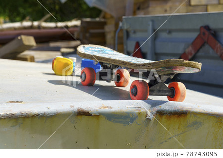 Old shabby kids skateboard on the hood of old car outdoors Old shabby kids skateboard on the hood of old car outdoors 78743095