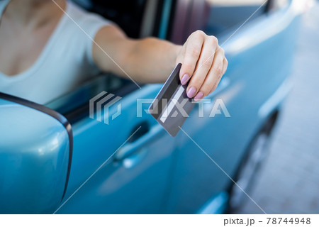A woman pays with a credit card while refueling a car A woman pays with a credit card while refueling a car 78744948