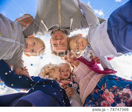 Friendly family hugs against the blue sky. 78747366
