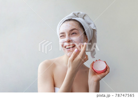 Beauty portrait of woman in towel on head with white nourishing mask or creme on face, white background isolated 78747565