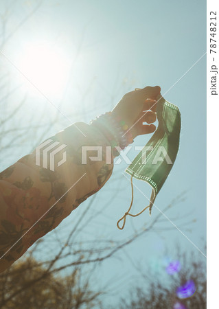 Little girl hold her mask, against the sky; end of quarantine or pandemic, back to normal Little girl hold her mask, against the sky; end of quarantine or pandemic, back to normal 78748212