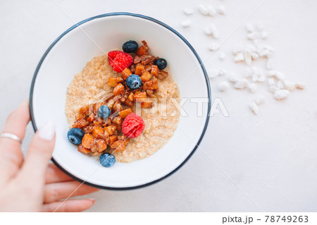 Oatmeal porridge in bowl topped with fresh blueberries, cranberries and homemade crunchy granola 78749263