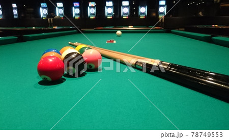 スポットライト下のナインボールがセットされたビリヤード台とキュー 78749553