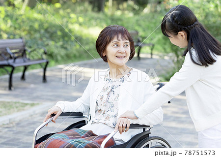 車椅子に乗った祖母と話す孫娘 78751573