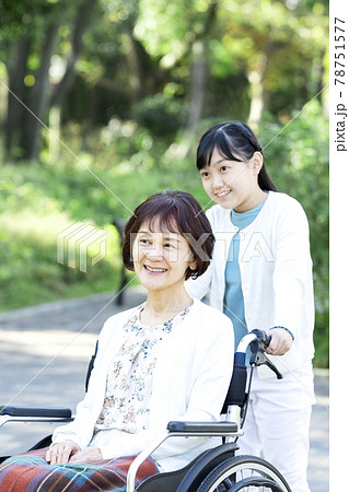 祖母の車椅子を押す孫娘 78751577
