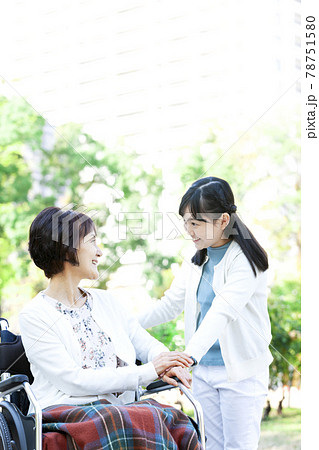 車椅子に乗った祖母と話す孫娘 78751580