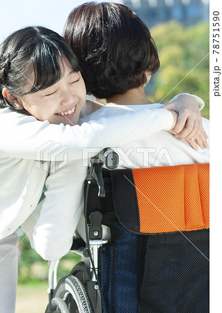 車椅子に座る祖母に抱きつく孫娘 車椅子に座る祖母に抱きつく孫娘 78751590