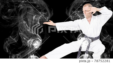 Composition of male martial artist over trails of smoke on black background Composition of male martial artist over trails of smoke on black background 78752281