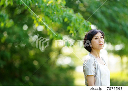 緑の中で遠くを見る中年女性　緑の中に立つミドル女性 78755934