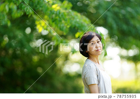 緑の中、立ち去る中年女性　真顔で振り向くミドル女性 78755935