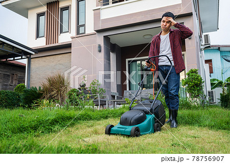 tired man using lawn mower cutting grass at home 78756907