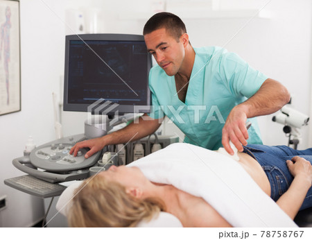 Man doctor examines a mature woman at abdomen with ultrasound 78758767