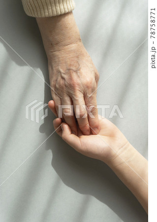 カーテン越しの光の下で愛しい孫の手をつかむ祖母の手 カーテン越しの光の下で愛しい孫の手をつかむ祖母の手 78758771