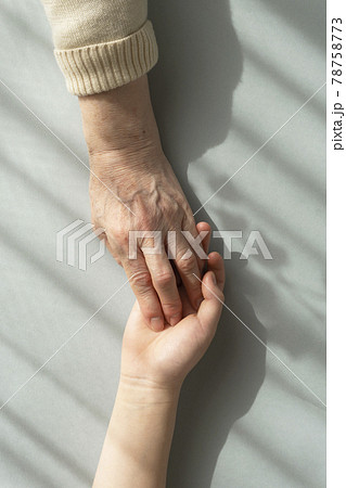 カーテン越しの光の下で愛しい孫の手をつかむ祖母の手 カーテン越しの光の下で愛しい孫の手をつかむ祖母の手 78758773