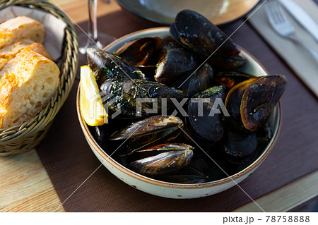 Delicious steamed in green sauce mussels, served at plate at table Delicious steamed in green sauce mussels, served at plate at table 78758888