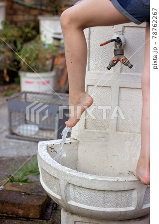 Little girl washing her feet on the decorative garden faucet 78762267