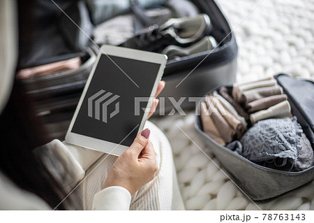A beautiful young girl in a white casual suit sits on the bed and uses a tablet. A beautiful young girl in a white casual suit sits on the bed and uses a tablet. 78763143