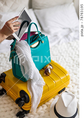 Woman hands ready travel journey putting tablet pc into handbag packing baggage at bedroom Woman hands ready travel journey putting tablet pc into handbag packing baggage at bedroom 78763195