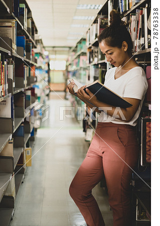 Young Asian women are searching for books and reading from the bookshelves in the college library to research and develop themselves in education Young Asian women are searching for books and reading from the bookshelves in the college library to research and develop themselves in education 78763338