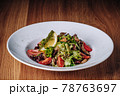 White Plate with Salad Stands on a Wooden Table in a Restaurant 78763697
