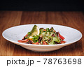 White Plate with Salad Stands on a Wooden Table in a Restaurant 78763698
