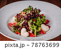 White Plate with Salad Stands on a Wooden Table in a Restaurant 78763699