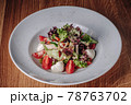 White Plate with Salad Stands on a Wooden Table in a Restaurant 78763702