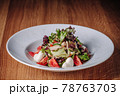 White Plate with Salad Stands on a Wooden Table in a Restaurant 78763703
