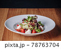 White Plate with Salad Stands on a Wooden Table in a Restaurant 78763704