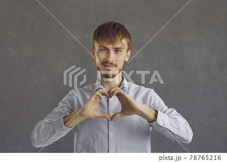 Caucasian red-haired man making heart gesture showing love and charity Caucasian red-haired man making heart gesture showing love and charity 78765216