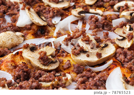 Close-up of pizza topped with mushrooms, onion and chopped meat. Macro shot of delicious products. 78765523